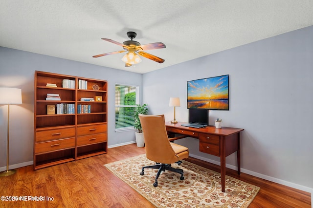 office space with ceiling fan, a textured ceiling, baseboards, and wood finished floors