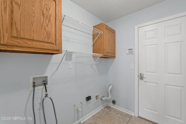 clothes washing area featuring cabinet space, light tile patterned floors, baseboards, a textured ceiling, and washer hookup