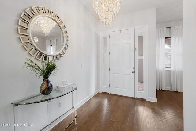 foyer featuring wood-type flooring, baseboards, and an inviting chandelier