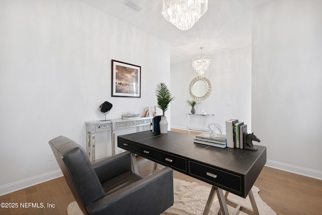 office space featuring baseboards, visible vents, a notable chandelier, and wood finished floors