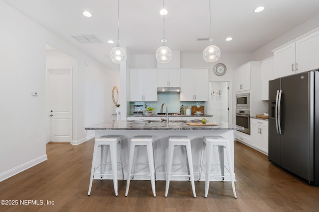 kitchen with stainless steel appliances, a breakfast bar, backsplash, and white cabinets