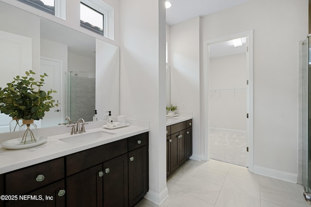 bathroom featuring tile patterned flooring, vanity, baseboards, a spacious closet, and a stall shower