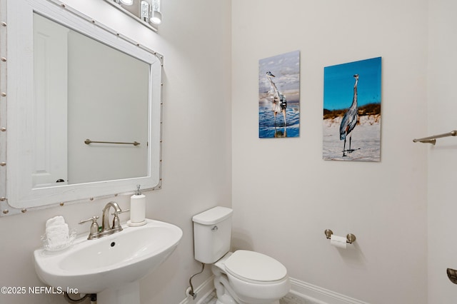 bathroom featuring a sink, toilet, and baseboards