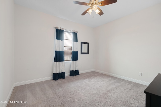 carpeted empty room featuring a ceiling fan and baseboards