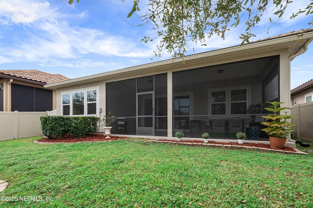 back of house featuring a yard, fence, and a sunroom