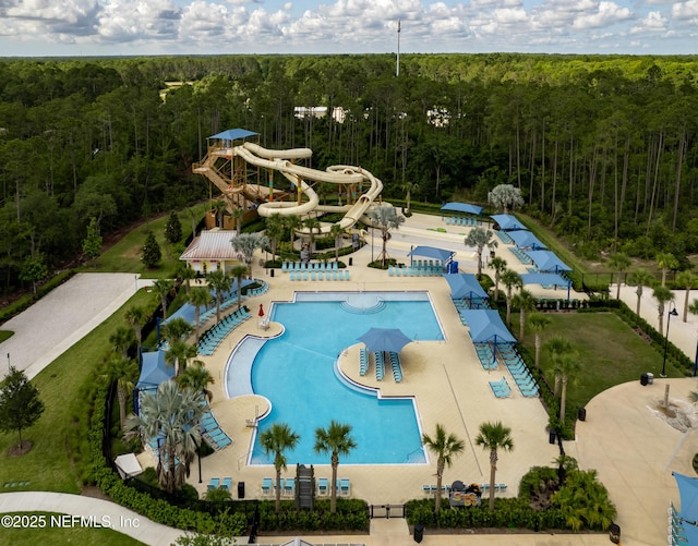 community pool with a forest view, fence, and a water slide