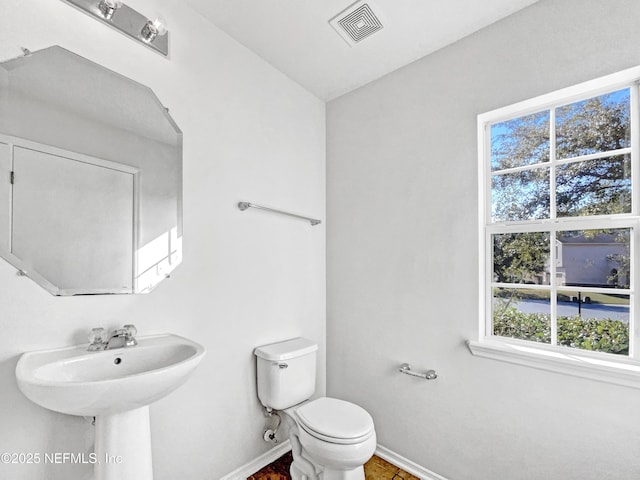 half bathroom with toilet, baseboards, and visible vents