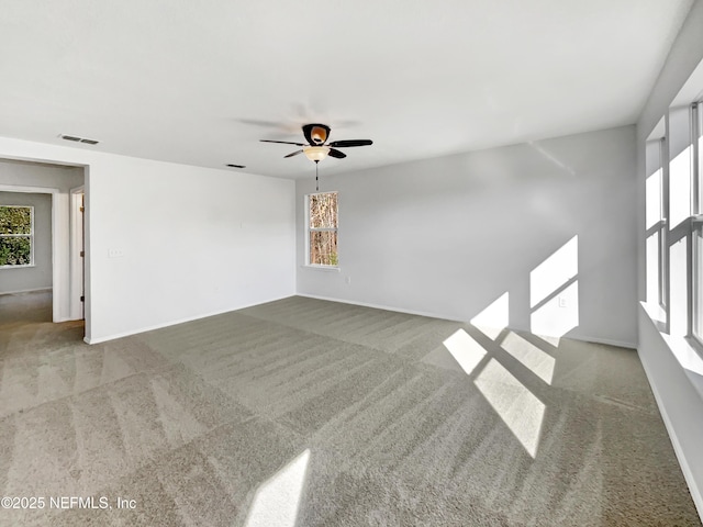 empty room featuring baseboards, visible vents, a ceiling fan, and light colored carpet