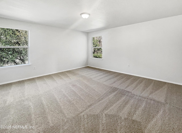 unfurnished room with carpet flooring and baseboards