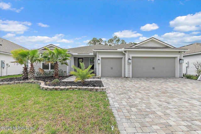 view of front facade featuring decorative driveway, an attached garage, and a front yard