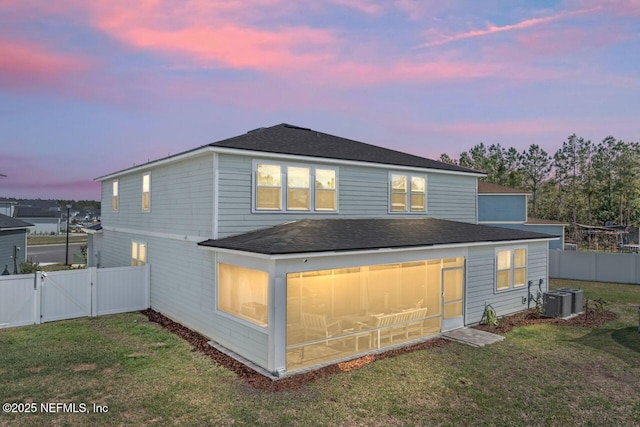 rear view of house featuring a fenced backyard, central AC, a sunroom, a lawn, and a gate