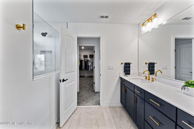 bathroom featuring visible vents, vanity, a textured ceiling, and tiled shower