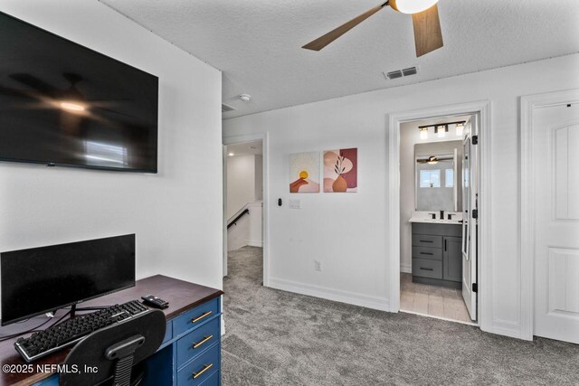 home office featuring light carpet, a ceiling fan, visible vents, and a textured ceiling