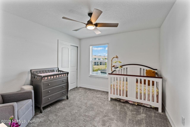 carpeted bedroom featuring a crib, a textured ceiling, baseboards, and a closet