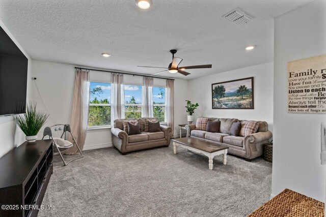 carpeted living area with a textured ceiling, recessed lighting, visible vents, baseboards, and a ceiling fan