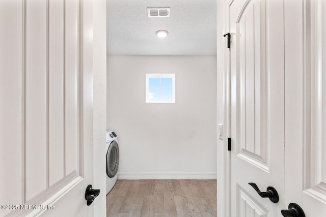 laundry area featuring a textured ceiling, laundry area, visible vents, light wood finished floors, and washer / clothes dryer