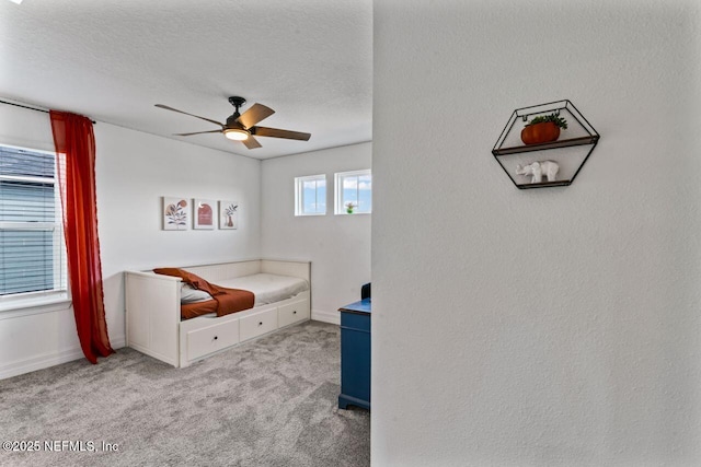 carpeted bedroom featuring a textured ceiling, ceiling fan, and baseboards