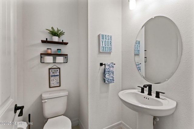 bathroom featuring a sink, toilet, and baseboards