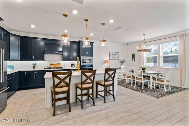 kitchen featuring wood finish floors, visible vents, a kitchen breakfast bar, light countertops, and appliances with stainless steel finishes