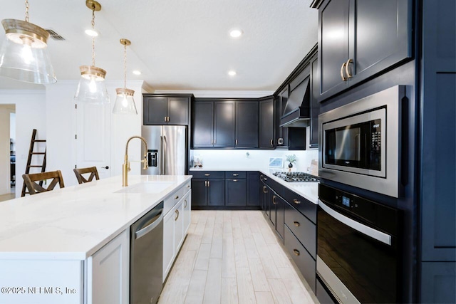 kitchen featuring a sink, visible vents, appliances with stainless steel finishes, a center island with sink, and custom range hood