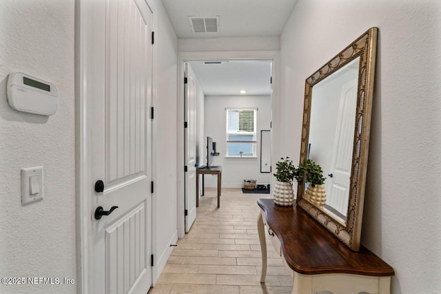 corridor with baseboards, visible vents, and wood finish floors