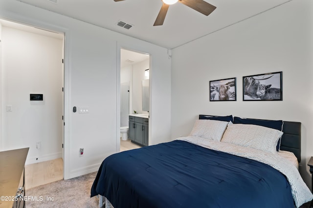 bedroom with connected bathroom, light colored carpet, a ceiling fan, baseboards, and visible vents