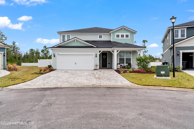 traditional home with decorative driveway, fence, board and batten siding, and a front yard