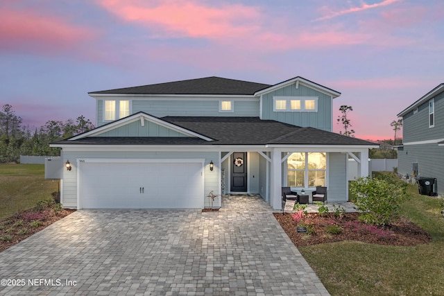 view of front of property featuring a garage, decorative driveway, board and batten siding, and fence