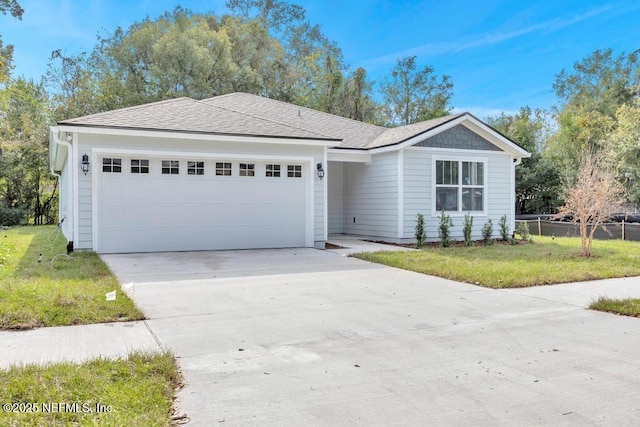 ranch-style house featuring a shingled roof, a front yard, fence, a garage, and driveway