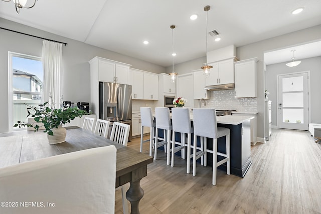 kitchen with white cabinetry, pendant lighting, light countertops, and stainless steel fridge with ice dispenser