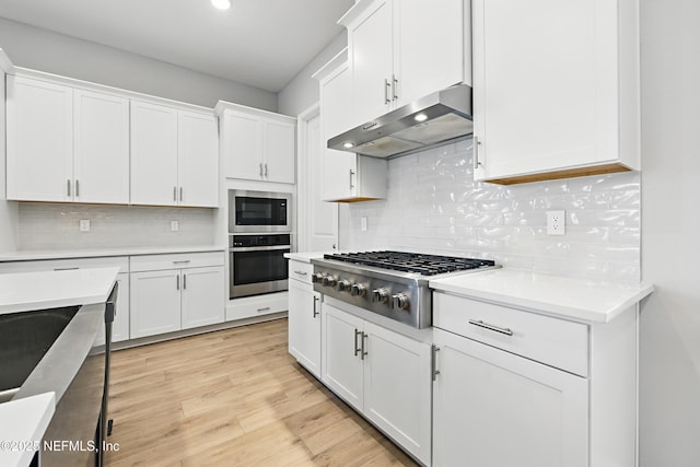 kitchen featuring light countertops, appliances with stainless steel finishes, white cabinets, and under cabinet range hood