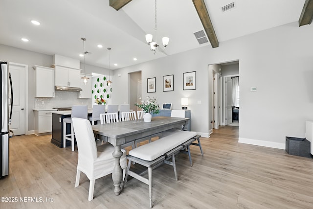 dining room featuring a chandelier, visible vents, vaulted ceiling with beams, and light wood finished floors