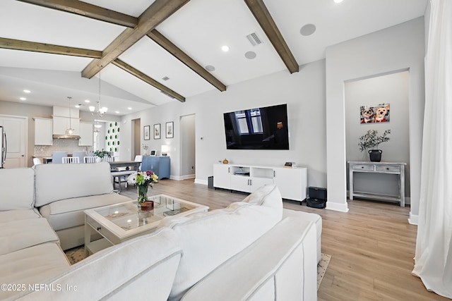 living area with baseboards, visible vents, vaulted ceiling with beams, an inviting chandelier, and light wood-style floors