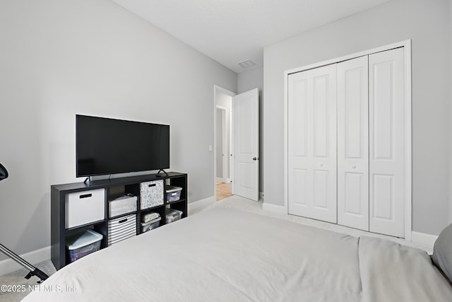 bedroom featuring a closet, light carpet, and baseboards