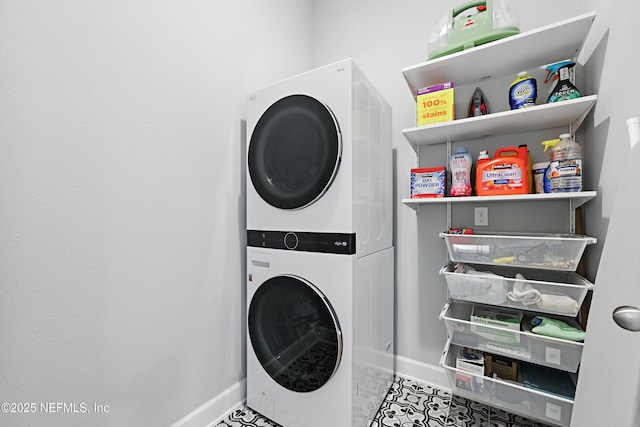 clothes washing area featuring laundry area, stacked washer / dryer, and baseboards