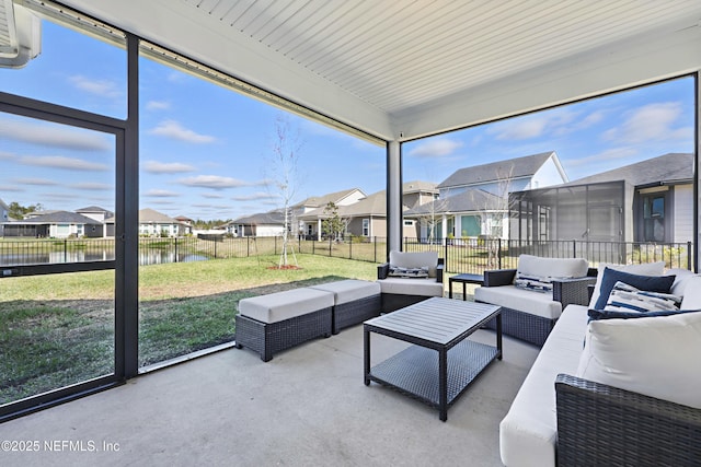 sunroom with a water view, a residential view, and a healthy amount of sunlight