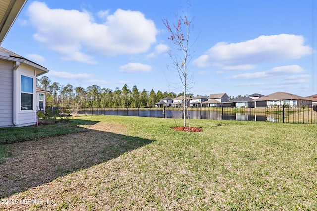 view of yard with a residential view, a water view, and a fenced backyard