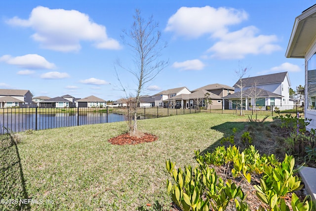 view of yard featuring a water view, a fenced backyard, and a residential view