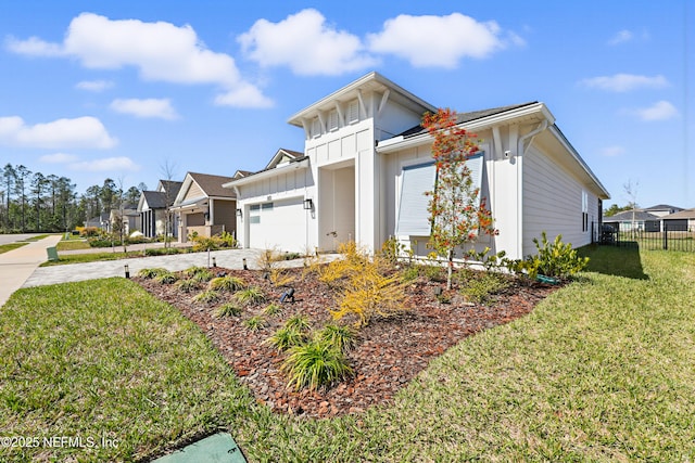 view of front of property with concrete driveway, board and batten siding, a front yard, fence, and a residential view