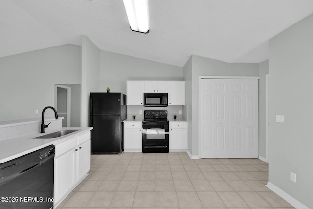 kitchen featuring lofted ceiling, a sink, white cabinetry, light countertops, and black appliances