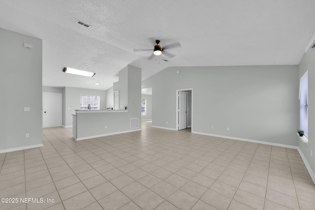 unfurnished living room featuring vaulted ceiling, visible vents, ceiling fan, and a textured ceiling