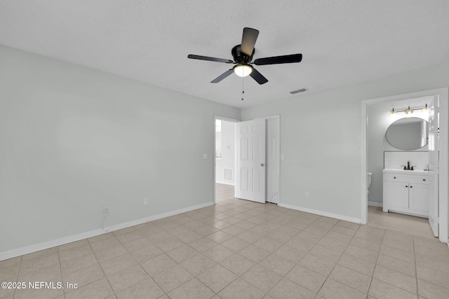 unfurnished bedroom featuring baseboards, connected bathroom, visible vents, and a textured ceiling