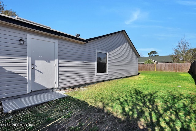 rear view of property featuring a yard and fence