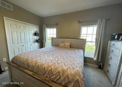 bedroom with light colored carpet, a closet, visible vents, and baseboards