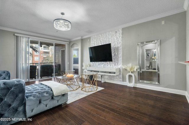 living room featuring ornamental molding, a textured ceiling, wood finished floors, a chandelier, and baseboards