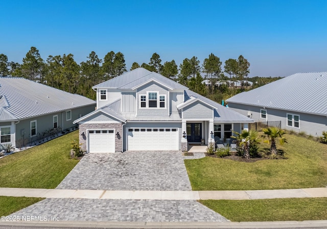 view of front of property featuring an attached garage, covered porch, decorative driveway, board and batten siding, and a front yard