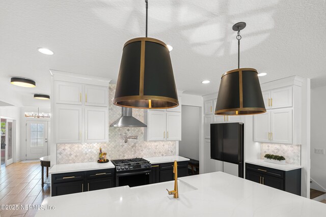 230 Marquesa Cir, Saint Johns, FL 32259 - kitchen featuring white cabinets, wall chimney exhaust hood, dark cabinets, freestanding refrigerator, and stainless steel range with gas stovetop