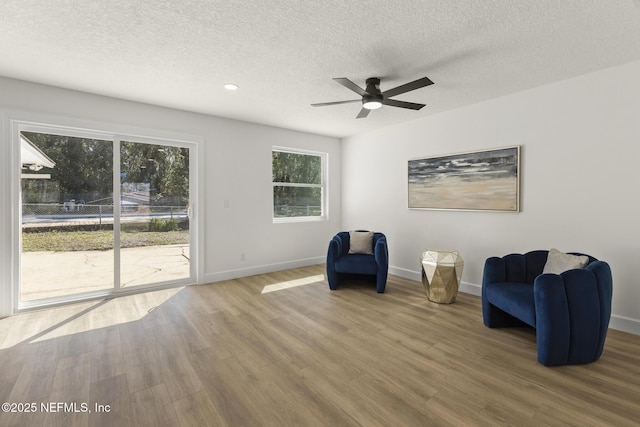 unfurnished room featuring ceiling fan, a textured ceiling, baseboards, and wood finished floors