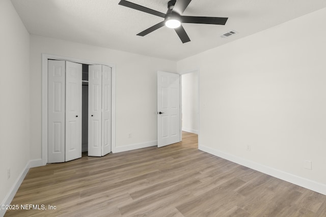 unfurnished bedroom with visible vents, baseboards, light wood-style flooring, ceiling fan, and a closet