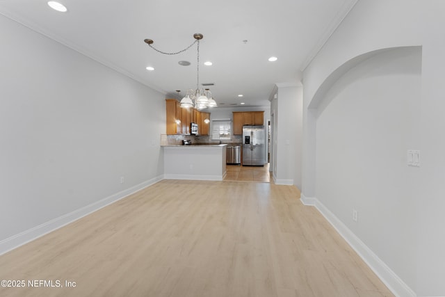 unfurnished living room featuring light wood-style floors, baseboards, ornamental molding, and arched walkways